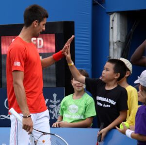 Tennis star Novak Djokovic gives a high five to a young fan